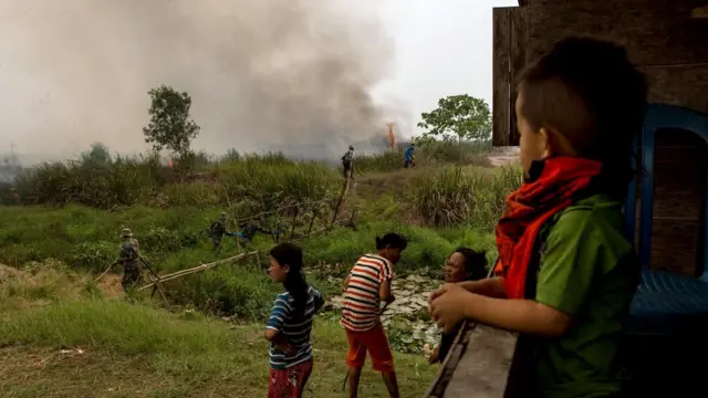 Warga di Sungai Rambutan, Ogan Ilir, Sumatera Selatan melihat upaya pemadaman di lahan gambut yang terbakar di dekat rumah mereka, Oktober 2015.