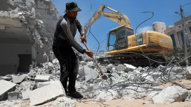 عمال فلسطينيون يزيلون أنقاض المباني التي دمرها القصف الإسرائيلي خلال الصراع بين إسرائيل وحماس في مايو/ أيار