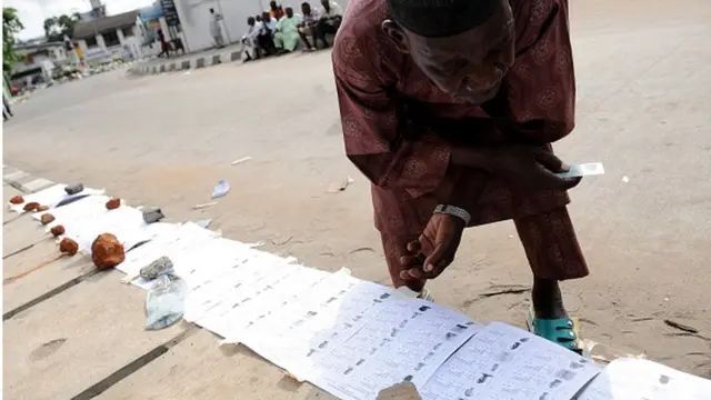 Ọkinrin kan n se ayẹwo awọn iwe akọdsilẹ orukọ awọn oludibo