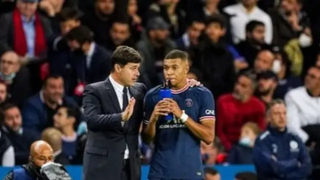 Mauricio Pochettino talks to Kylian Mbappe in front of PSG fans
