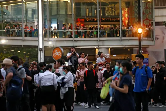 People stand outside the Central World Complex after it was evacuated due to a fire, in Bangkok, Thailand, April 10, 2019. REUTERS