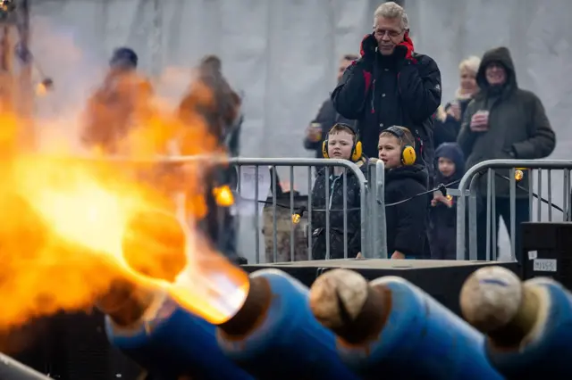 In Ommen, the Netherlands, milk cans fire footballs out the end of with lots of fire as families look on