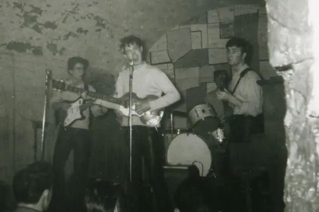 披头士四子在利物浦的卡文俱乐部演出：主音保罗·麦卡特尼（中）、乔治·哈里森（右）、约翰·列侬（左）、皮特·贝斯特（后）（7/1961）
