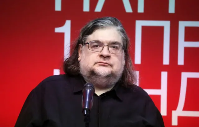 Портрет длинноволосого мужчины в очках средних лет