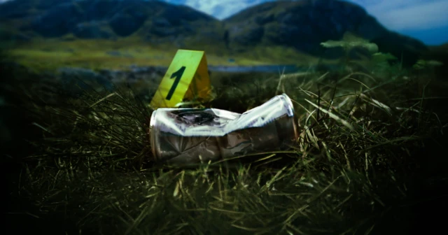 Lata de Red Bull amassada na grama, diante de um marcador amarelo com o número um