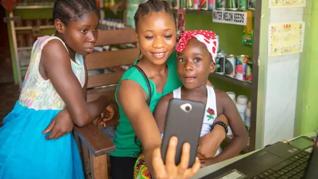 Une femme, avec ses enfants, tenant un smartphone.