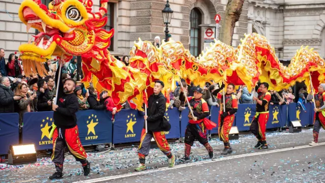 衛志樑是一名短黑髮、留鬍鬚男子，走在一條紅黃色中式龍的前方。他身穿紅黑色衣服，手持連接龍頭的長杆。