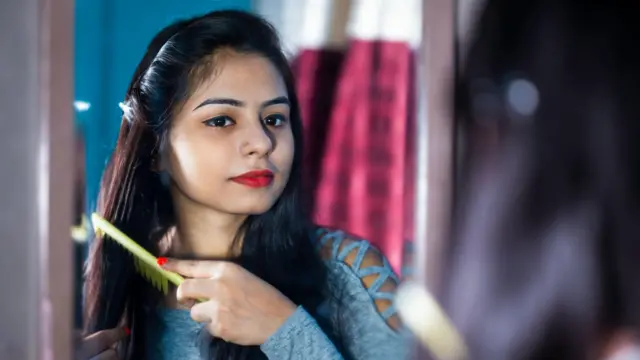 વાળ ઓળી રહેલાં મહિલાની પ્રતીકાત્મક તસવીર