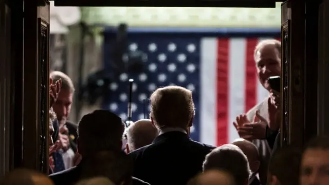 Trump de espaldas entrando a la sala