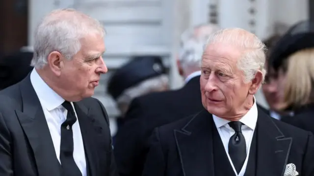 Prince Andrew speaks with King Charles at the funeral of Katharine, Duchess of Kent, in September. Both are wearing black suits and white shirts.