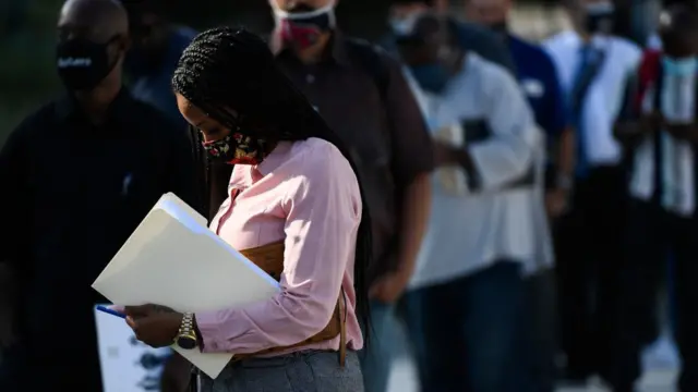 Una mujer espera frente a una fila.
