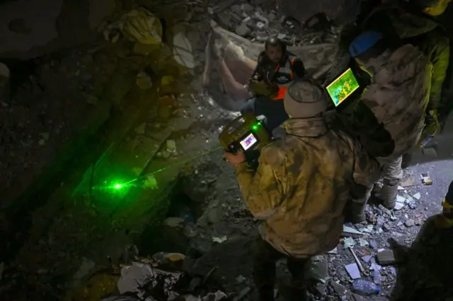 Un rescatista con sombrero y abrigo utiliza equipo de imagen térmica en el lugar de un terremoto en Turquía.