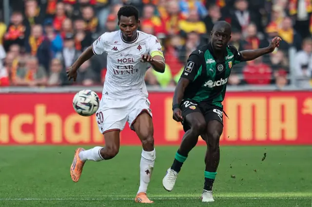 Malang Sarr (maillot vert et noir) et Habib Diallo (maillot blanc) se disputent le ballon lors du match de Ligue 1 opposant le RC Lens au FC Metz au Stade Bollaert-Delelis de Lens, en France, le 8 mars 2026. 