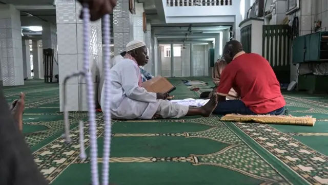 Des hommes musulmans lisent le Coran dans une mosquée le premier jour du mois sacré du Ramadan, à Treichville, un quartier populaire d'Abidjan, le 2 avril 2022