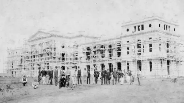 Homens posam diante do edifício, aindaapostas na betanoconstrução