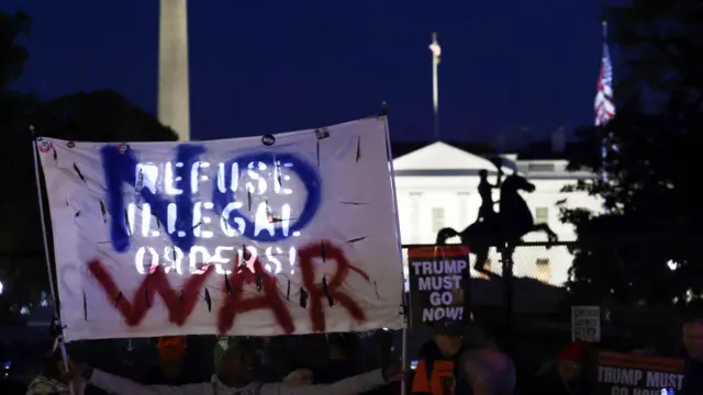 美國華盛頓白宮外反戰群眾舉起呼籲美軍「違抗非法命令」的標語布條,旁邊豎立著「特朗普必須下台」標語牌(7/4/2026)