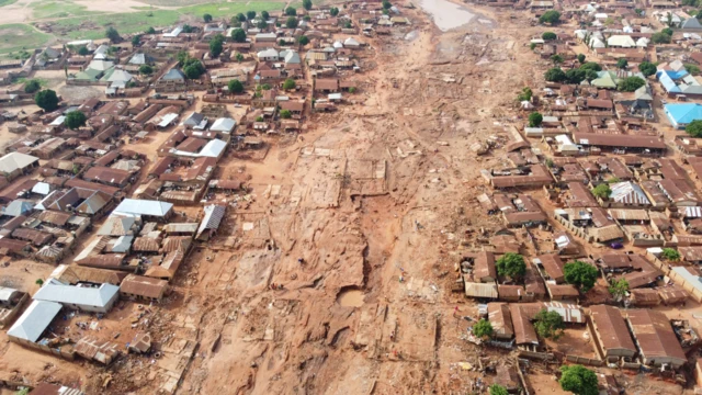 Dis na air view of how di community look like, wit brown roof and broken road