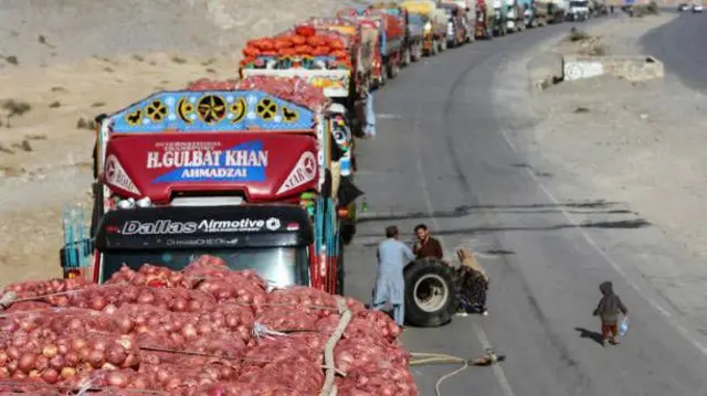 تصویر قطار لاریهای حامل کالاهای افغانی به شمول سبزیجات. در اولین لاری با پیاز دیده میشود. این لاریها رد مرز تورخم با پاکستان متوقف شدهاند.