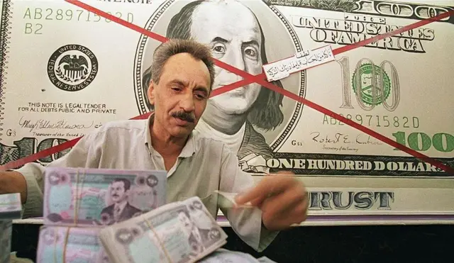 رجل يجلس أمام صورة الدولار وُضع عليها إشارة X وأمامه عملات عراقية عليها صورة صدام حسين