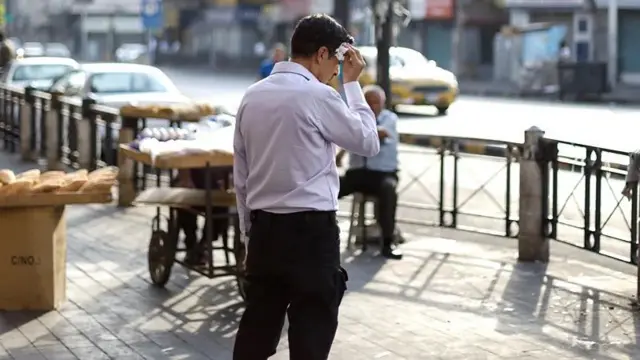 Homem com um lenço secando o suor na testa