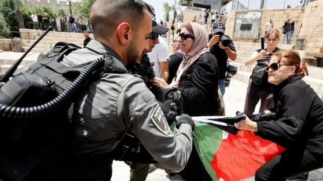 جندي إسرائيلي ينزع علم فلسطين من سيدة فلسطينية