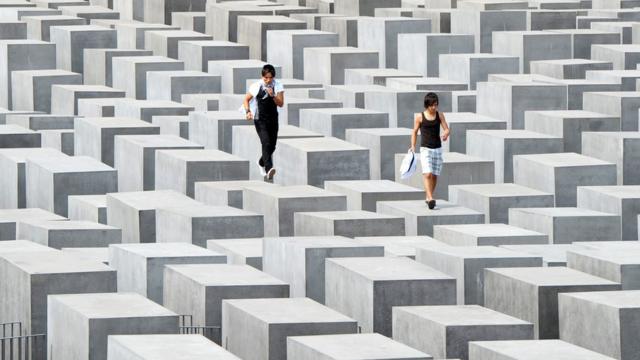 Dos visitantes caminan sobre los pilares del monumento al holocausto en Berlín. Foto de 2010.