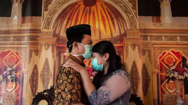 Pasangan Indonesia yang baru menikah berciuman sambil memakai masker saat pandemi Covid-19.