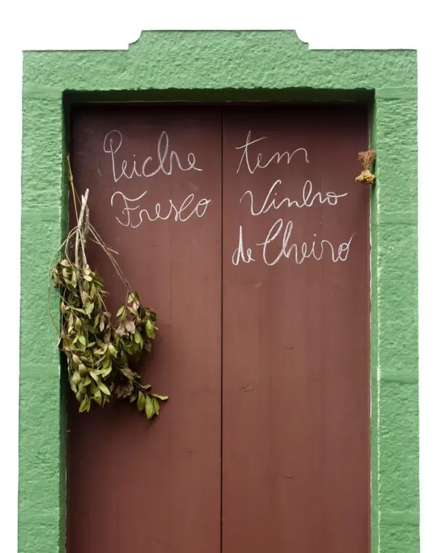 Una puerta marrón rodeada de verde con palabras escritas en portugués