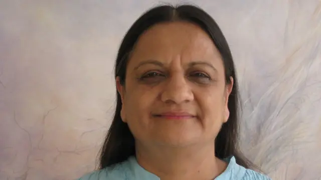 Mme Patani souriant et fixant la caméra