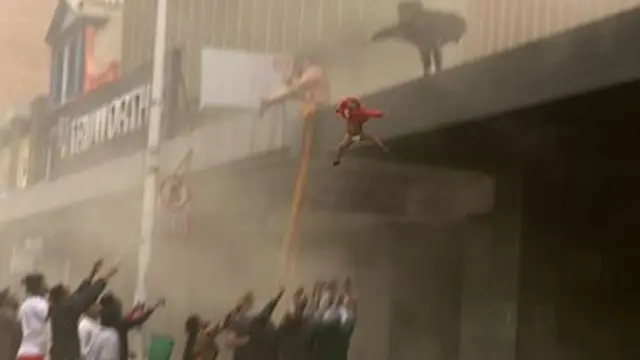 Niño siendo arrojado desde un edificio.