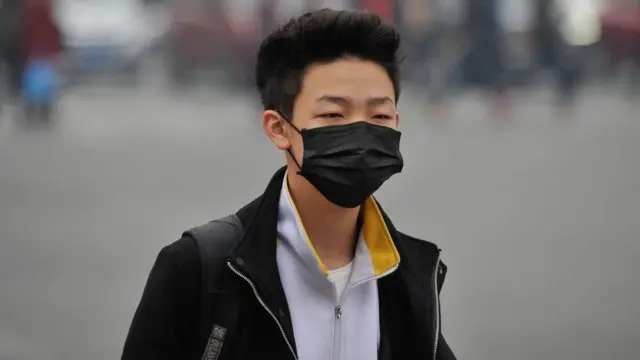 મોં પર માસ્ક પહેરીને જતા ચીની યુવકનો ફોટોગ્રાફ