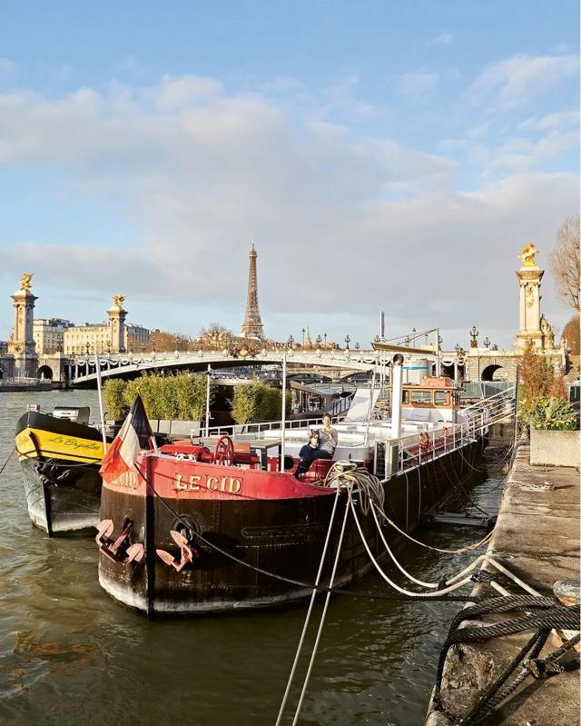 Fotografia colorida mostra uma barcaça no rio Sena
