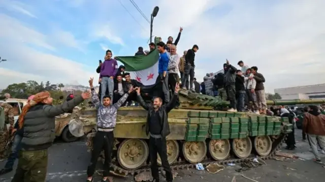 Танк устида Сурия байроғини кўтариб хурсанд бўлаётган сурияликлар