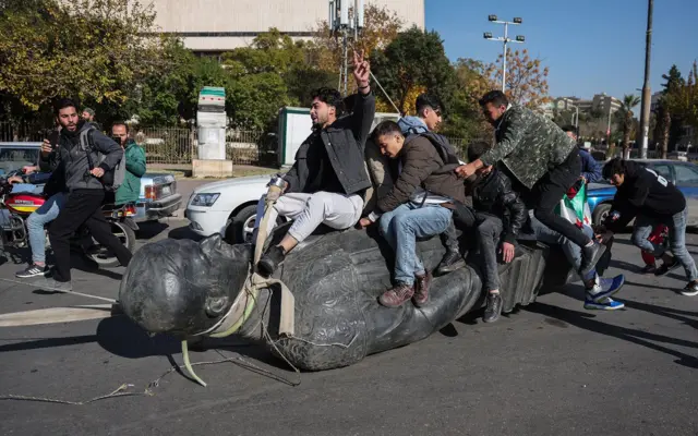 Estudantes arrastam uma estátua derrubada do falecido presidente Hafez al-Assad pela rua durante uma manifestação perto do campus da Universidadeinstagram betnacionalDamasco, na capital síria,instagram betnacional15instagram betnacionaldezembro