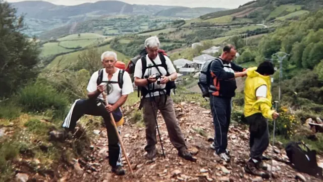 Juan Lopez junto a tres compañeros senderistas, con mochilas al hombro en una montaña