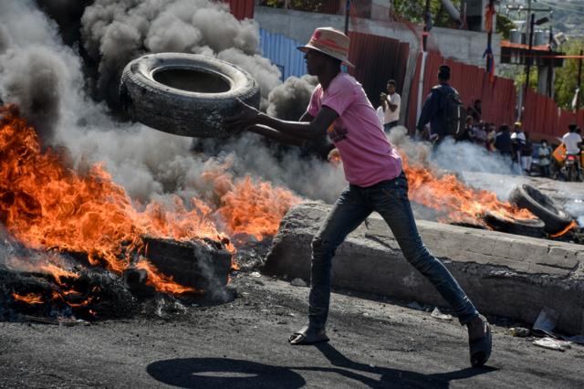 Un hombre arroja un neumático al fuego.