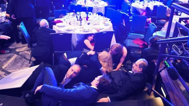 Silah seslerinin ardından konuklar masanın altına eğiliyor.