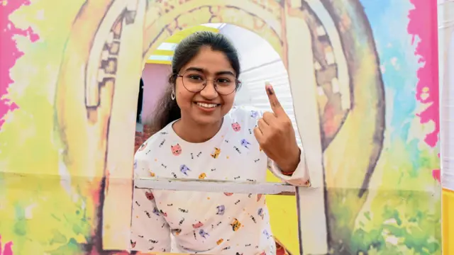 वोट के बाद अपनी उंगली पर लगी स्याही दिखाती एक युवा महिला मतदाता