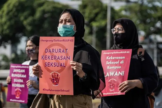 Aktivis perempuan Indonesia mengenakan masker wajah sambil memegang plakat, saat demonstrasi di depan di Dewan Perwakilan Rakyat Indonesia (DPR) untuk segera meloloskan Rancangan Undang-Undang Penghapusan Kekerasan Seksual (PKS) di Jakarta, Indonesia, Selasa, 7 Juli 2020. 