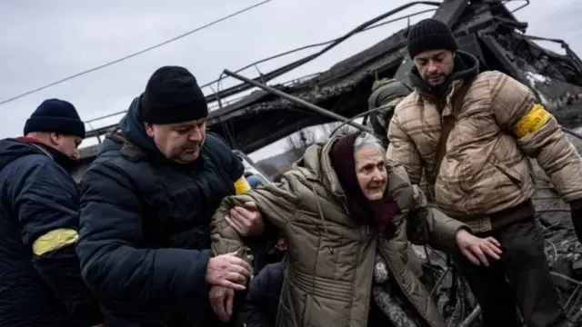 Des civils aident une femme âgée