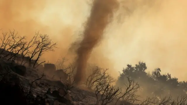Un torbellino de cenizas calientes y brasas se mueve a través de un incendio forestal que arde en las colinas de Santa Bárbara, California.