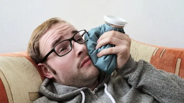 Una persona con una bolsa de hielo en la mejilla