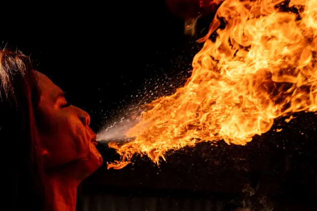 Женщина выдувает огонь