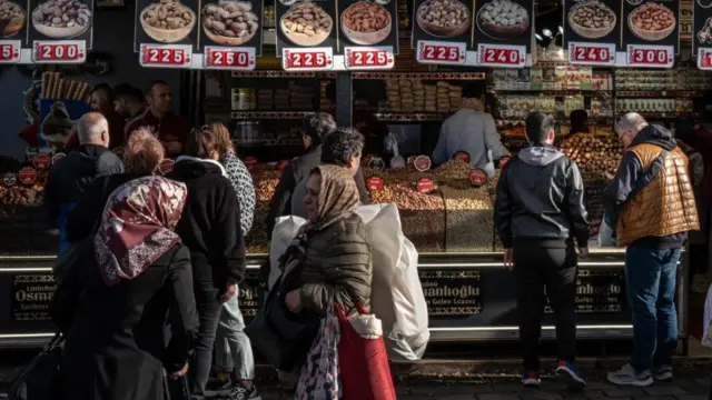 İstanbul'da çerez tezgahlarının önünde yürüyen kadın ve erkekler.