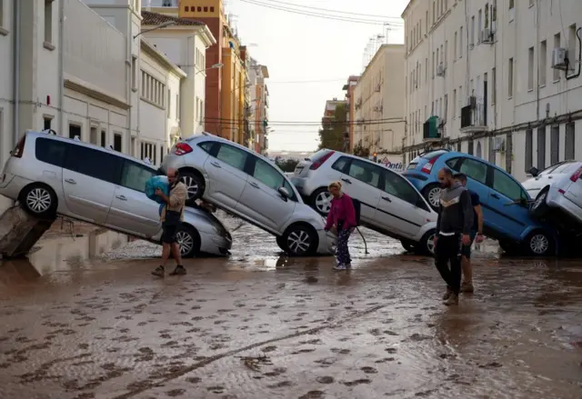 Vecinos caminan junto a autos amontonados tras las riadas en la Comunidad Valenciana