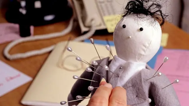 Un muñeco vudú vestido formal con alfileres