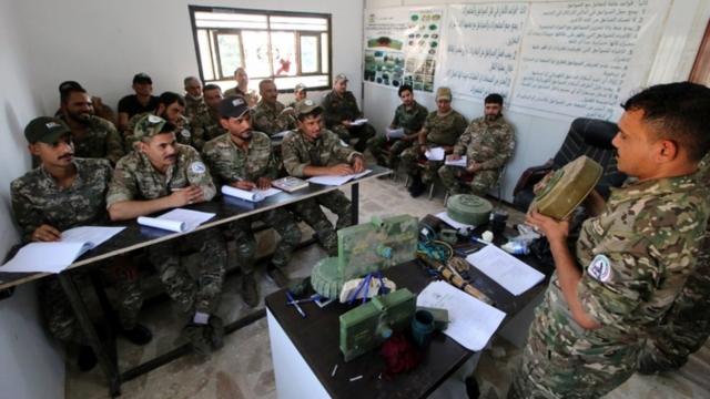 جنود بالحشد الشعبي يستمعون، في معسكر بالبصرة، إلى شرح من مدربهم على التعامل مع المتفجرات.