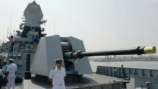 An Indian Navy sailor stands in front of the main gun of the INS Chennai ahead of its commissioning into the Indian Navy in Mumbai on November 18, 2016