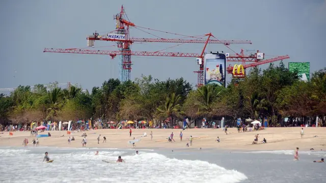 Wisatawan mengunjungi Pantai Kuta dengan latar belakang konstruksi Beach Walk senilai USD70 juta, 2 Februari 2011.