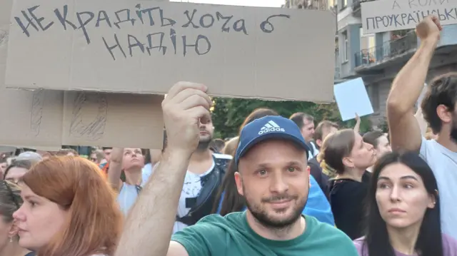 Мужчина с картонным плакатом на протесте.